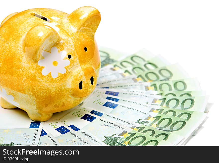 Yellow ceramic piggy bank on a pile of banknotes