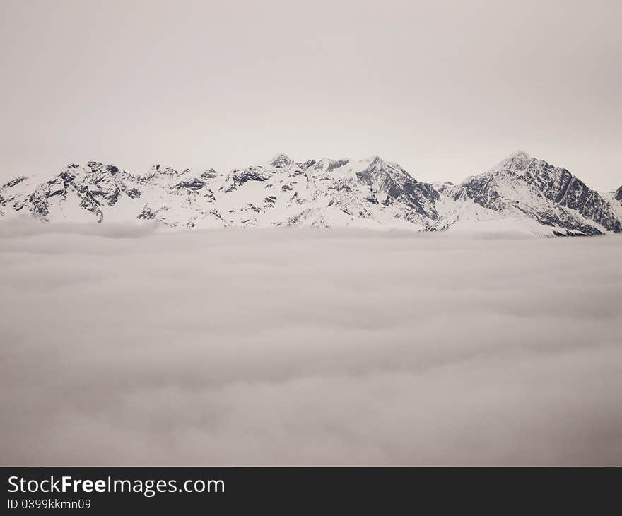 Top of snowy mountains over the clouds