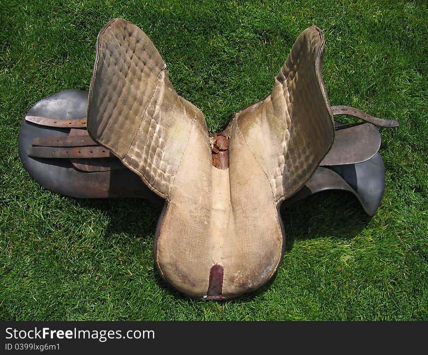 Very old English horse saddle on grass taken from the bottom side. Very old English horse saddle on grass taken from the bottom side