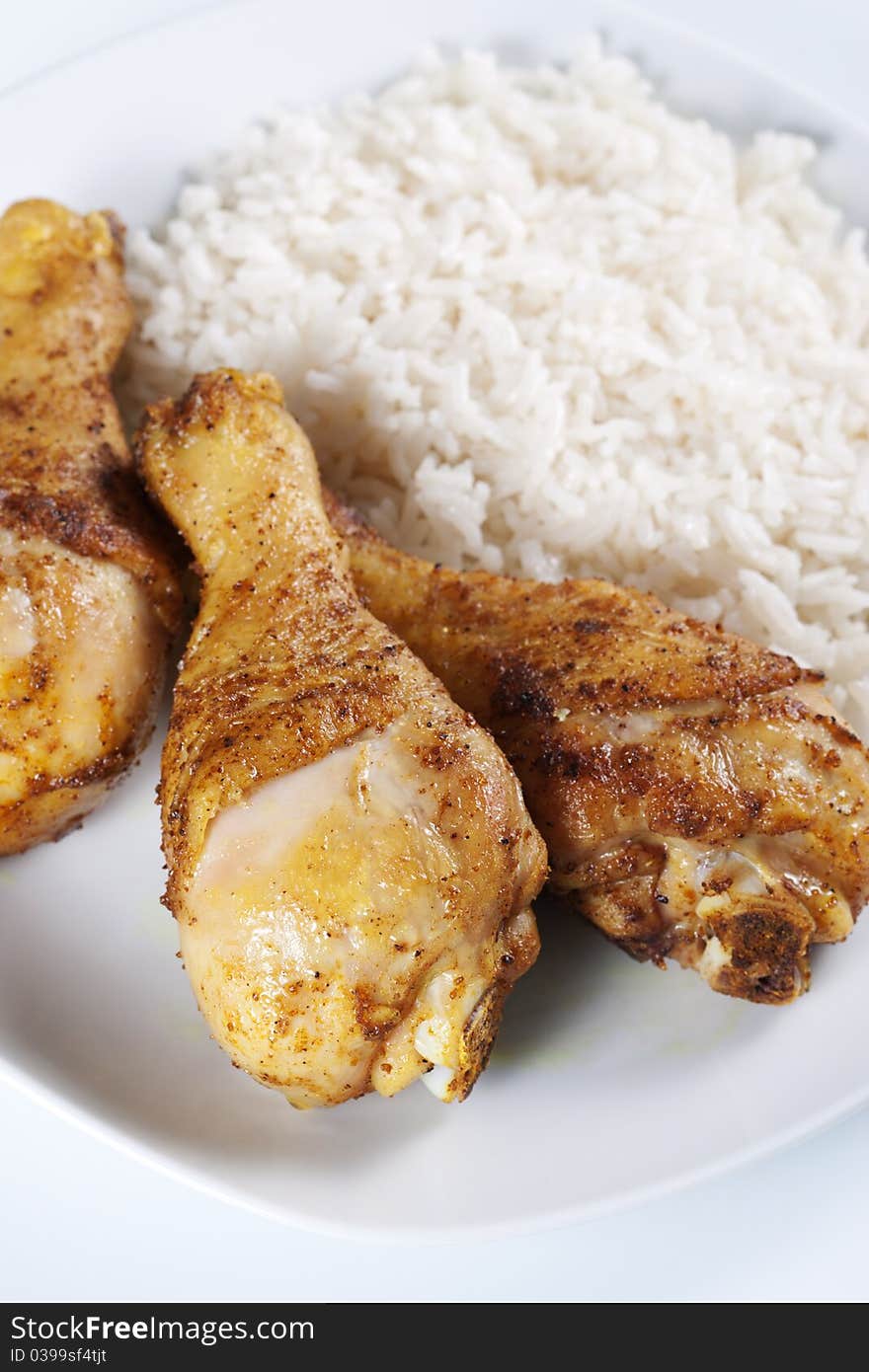 Roasted chicken legs with boiled rice on a plate