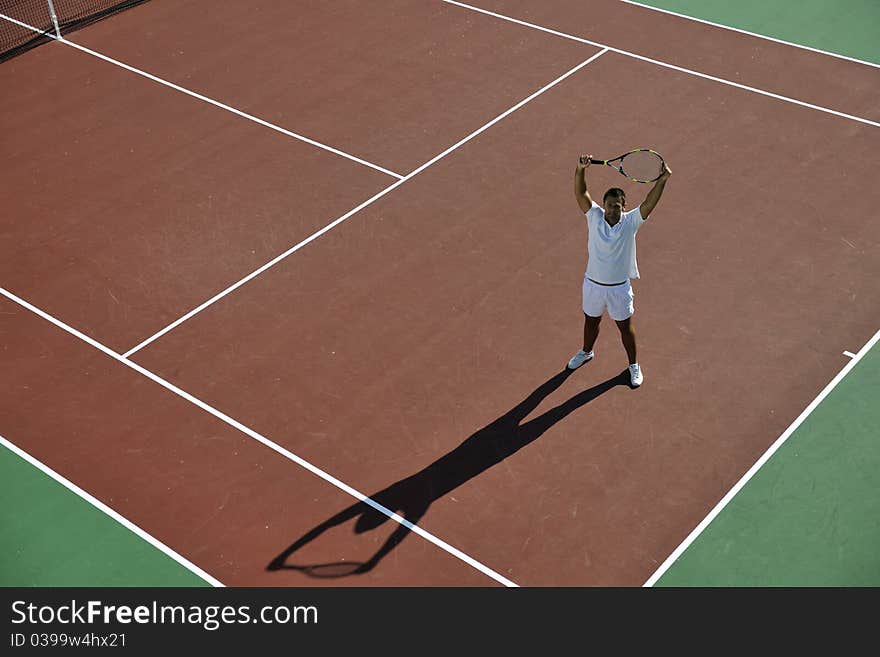 Young man play tennis outdoor on orange tennis field at early morning