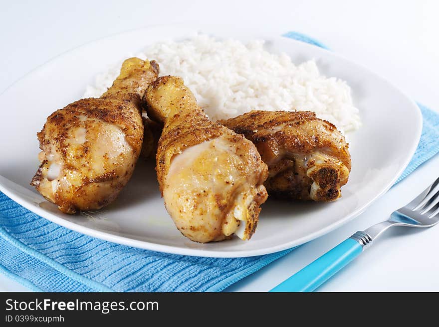 Roasted chicken legs with boiled rice on a plate