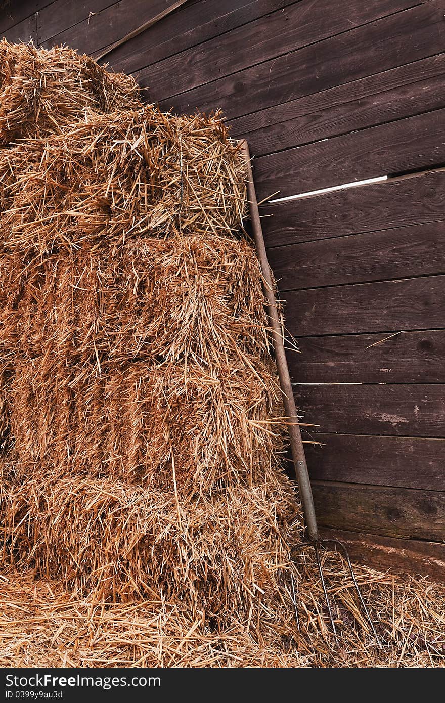 Idyllic scene with a pitchfork and straw in front of a cowshed