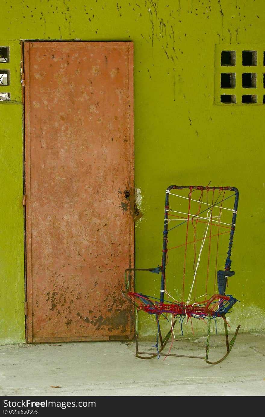 A front door of a bright green costa rican house with a home-made rocking chair by the door. A front door of a bright green costa rican house with a home-made rocking chair by the door.