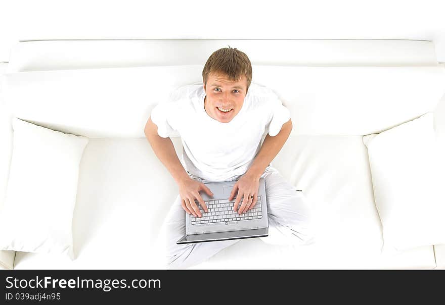 Portrait of a young man relaxing on couch while using a laptop