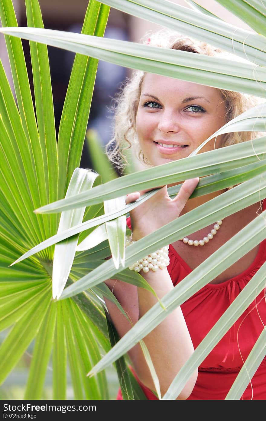 Young beautful woman looking through palm tree leaves. Young beautful woman looking through palm tree leaves