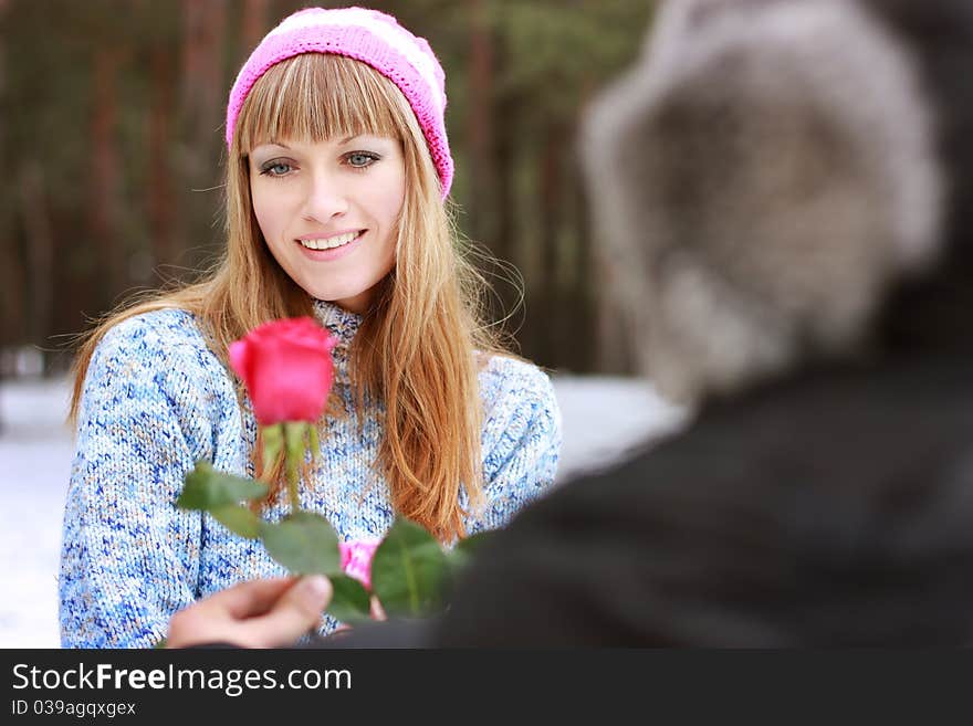 Man handing over a single red rose to young woman