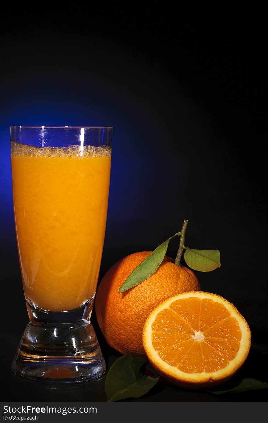 Natural orange juice in a glass and orange fruit, on black background shooting with blue gel. Natural orange juice in a glass and orange fruit, on black background shooting with blue gel