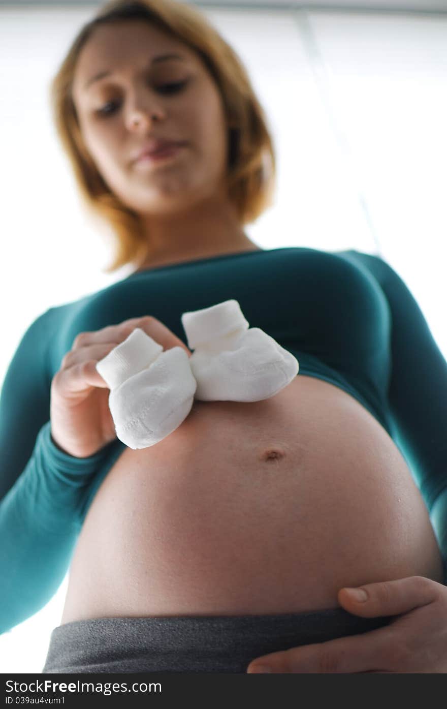 Pregnant woman holding baby shoes