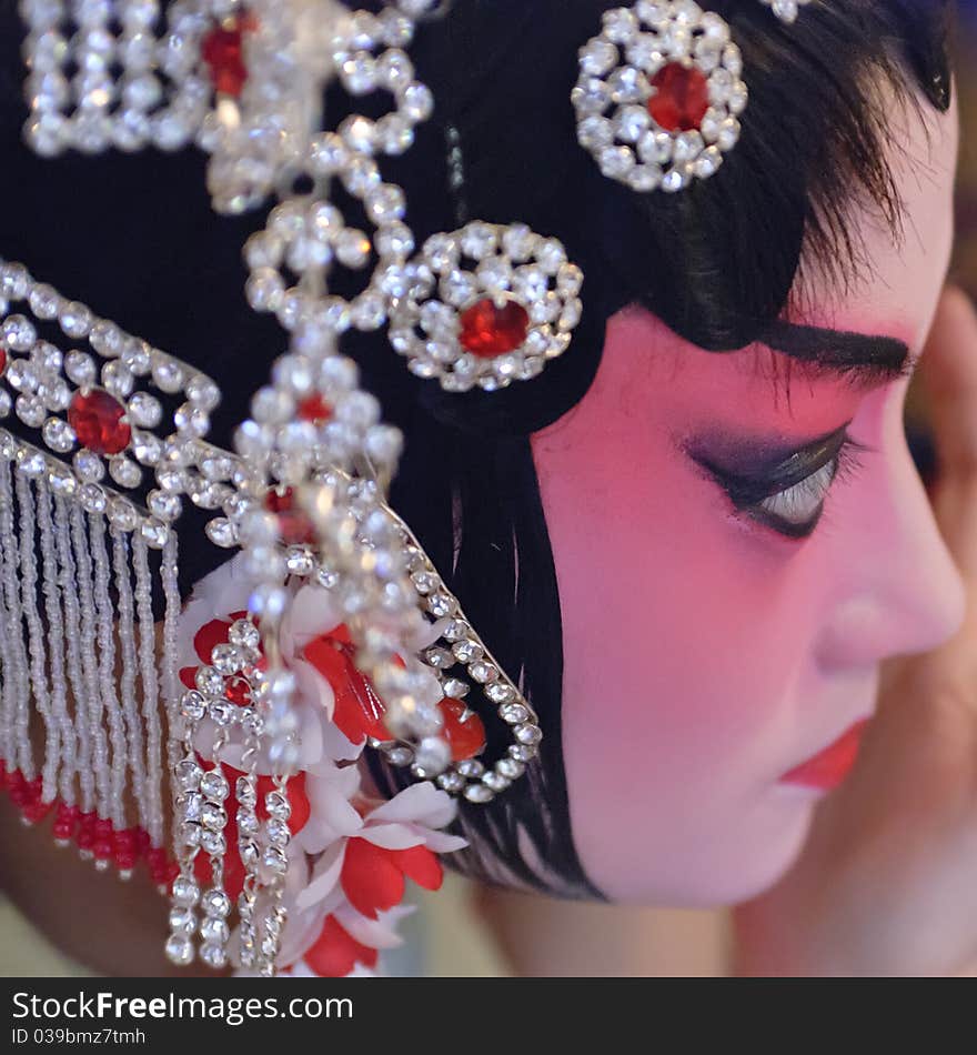 A chinese opera actress is painting her face backstage