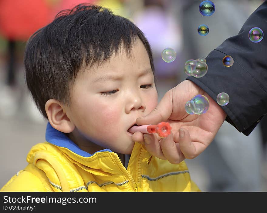 A child blowing soap bubbles in a park. A child blowing soap bubbles in a park