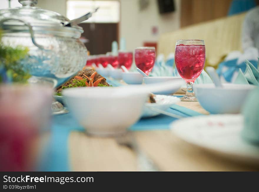 A row of glasses filled with water arranged in a row on a dining table with bokeh effect. A row of glasses filled with water arranged in a row on a dining table with bokeh effect