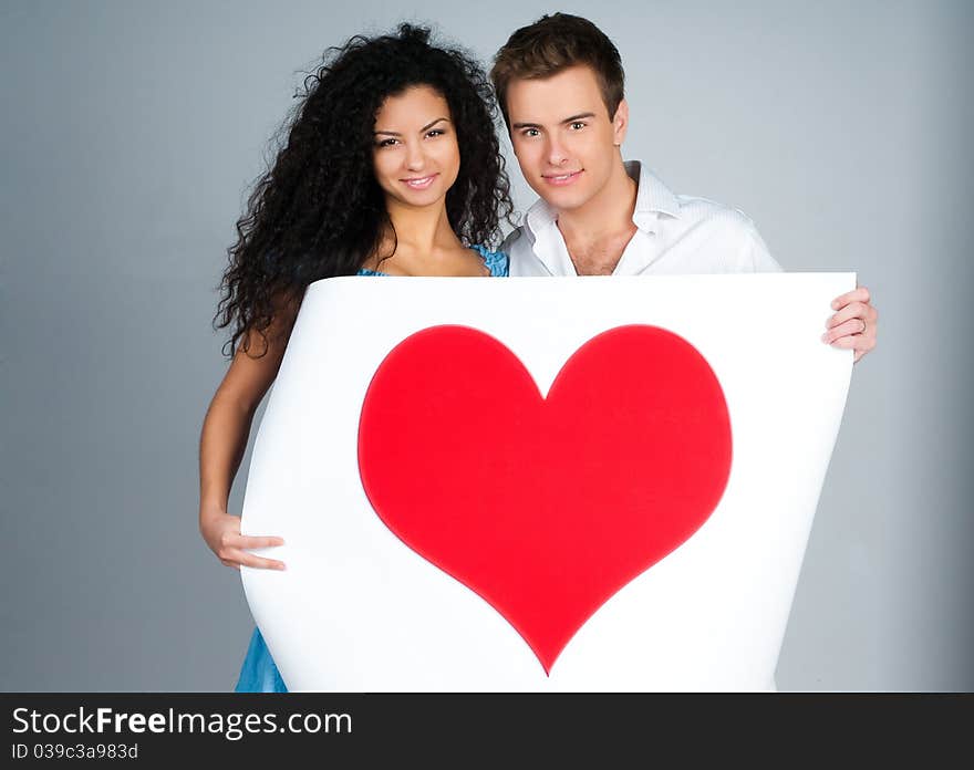 Beautiful young couple holding a red heart