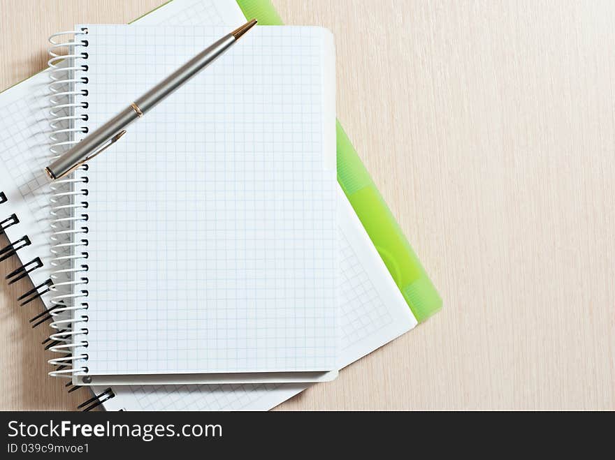 Blank spiral note pad with silver pen on wood desk. Blank spiral note pad with silver pen on wood desk