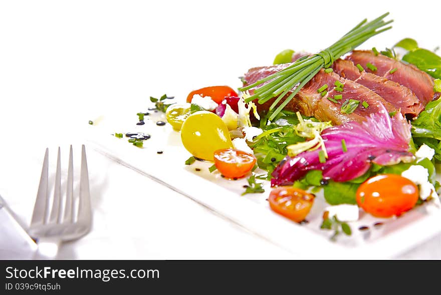 A prime cut of grilled, tender fillet beef on a healthy, and colourful herb salad. A prime cut of grilled, tender fillet beef on a healthy, and colourful herb salad.