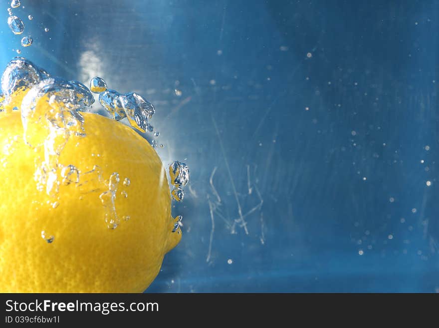 A yellow zesty lemon fully submerged in water.