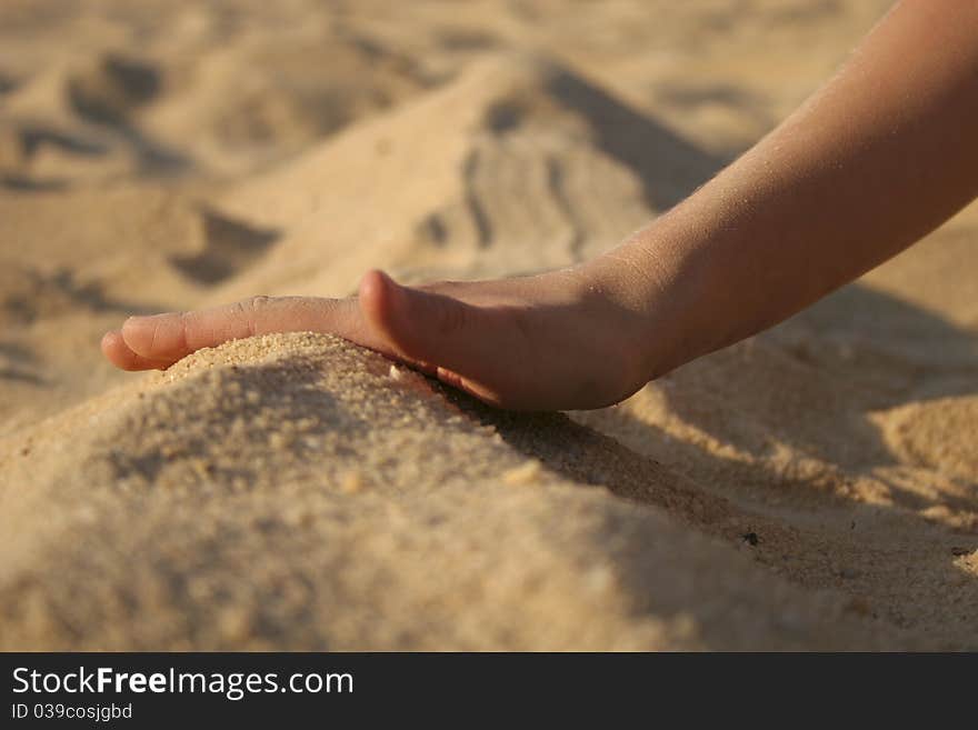 Child's hand playing in white sand on beach. Child's hand playing in white sand on beach