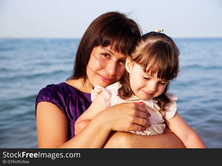 Mother hugging her daughter on sea background. Mother hugging her daughter on sea background