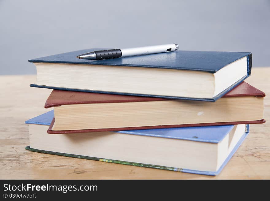 Pen lying on a pile of three books. Pen lying on a pile of three books