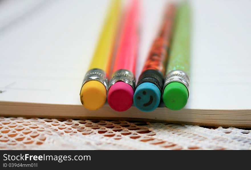 Four bright colored pencil erasers, with one smiling back.