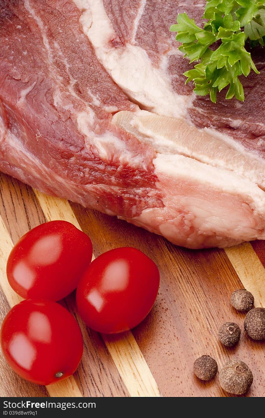 A piece of raw meat on a multilayer wooden kitchen cutting board.