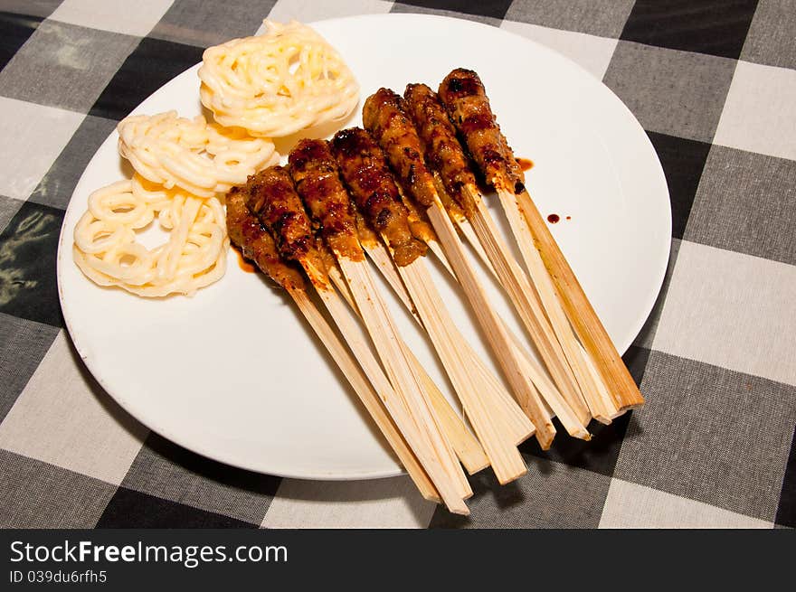 A traditional Balinese seafood skewers with crackers.