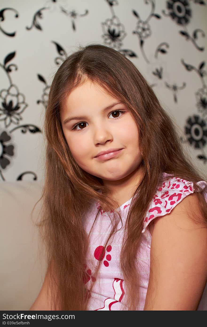 A happy little girl sitting on the sofa, smiling. A happy little girl sitting on the sofa, smiling