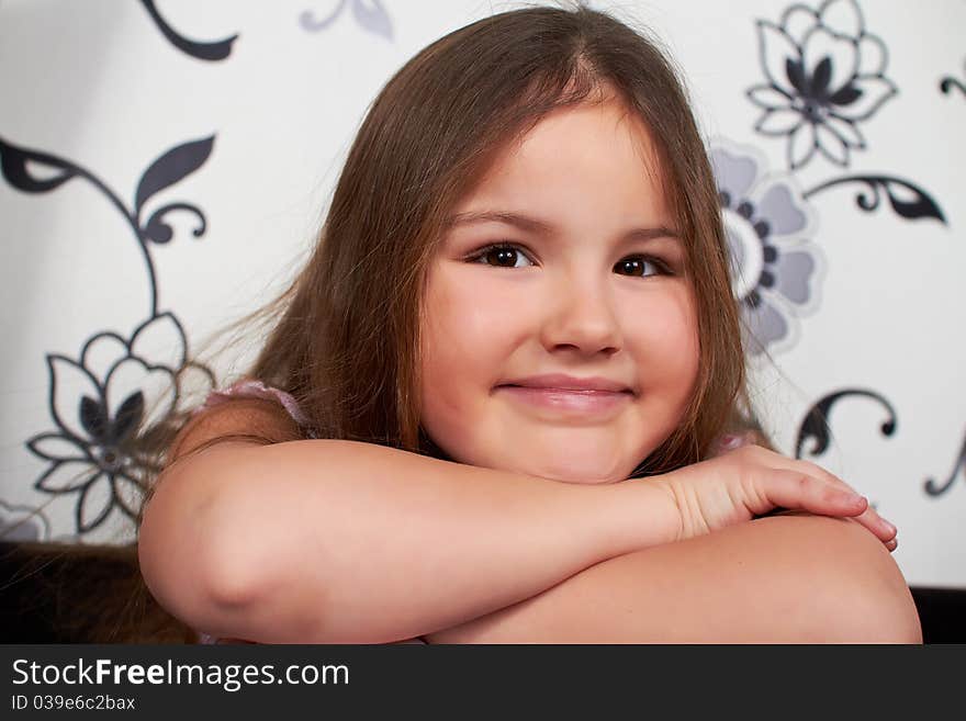 A happy little girl sitting on the sofa, smiling. A happy little girl sitting on the sofa, smiling