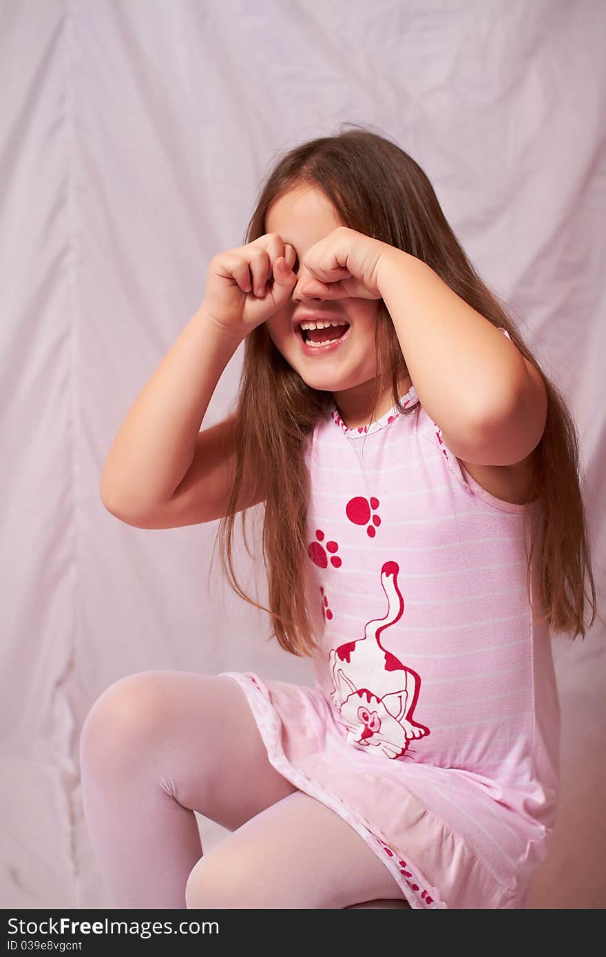 The little girl in a white-pink dress sits and weeps, wiping her tears with his fists. The little girl in a white-pink dress sits and weeps, wiping her tears with his fists.