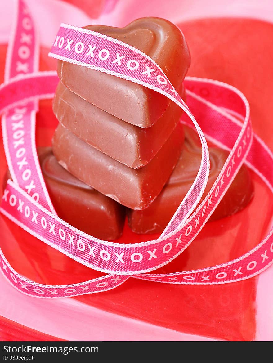 Stack of heart shaped chocolates wrapped with xoxoxo ribbon on a plate to be used for Valentine's Day or anniversaries, or romance. Stack of heart shaped chocolates wrapped with xoxoxo ribbon on a plate to be used for Valentine's Day or anniversaries, or romance
