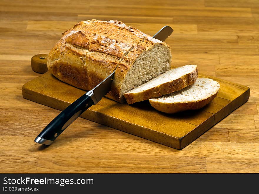 Wooden cutting board with white bread and knife