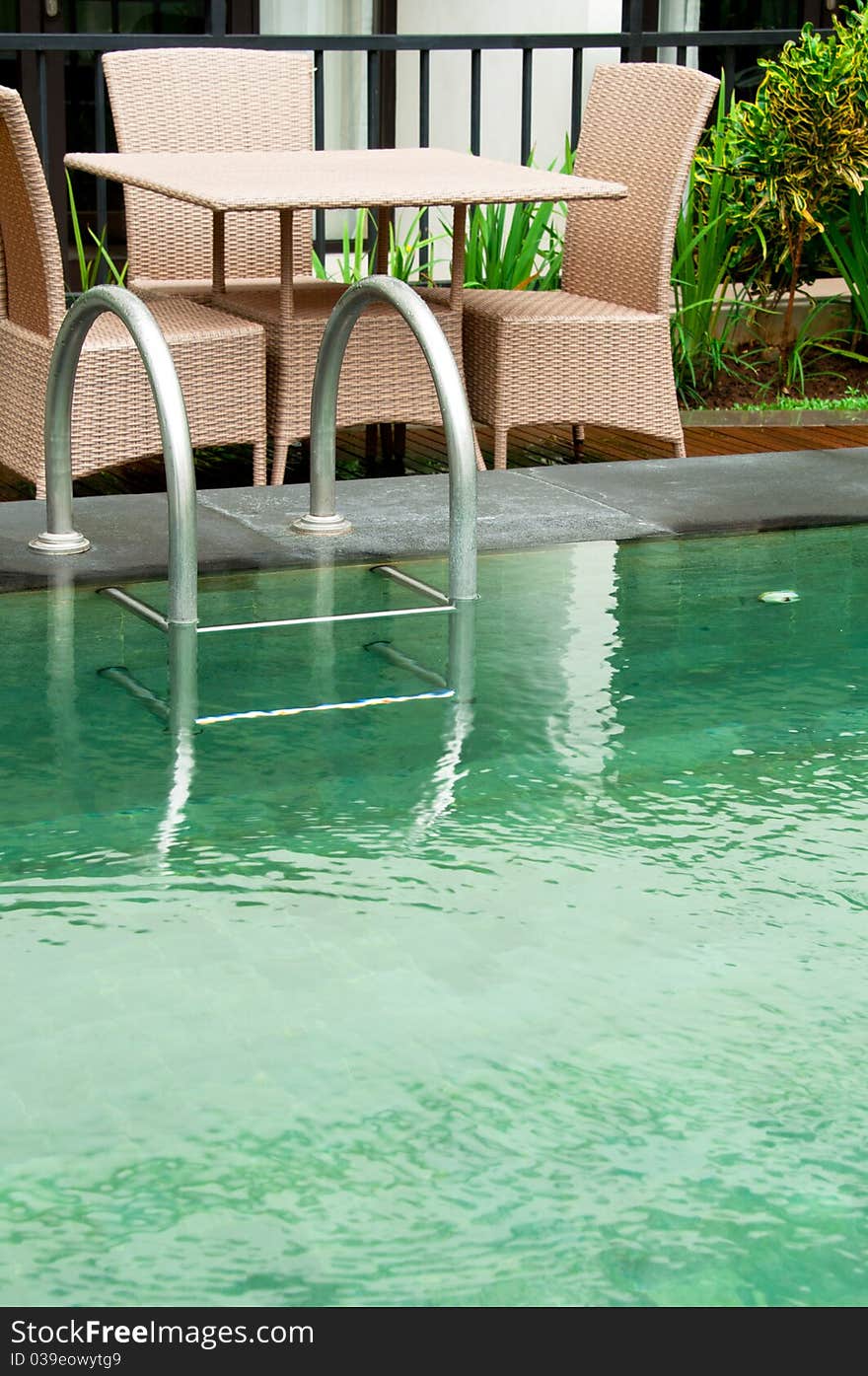 Poolside view of a ladder and wicker furniture. Poolside view of a ladder and wicker furniture