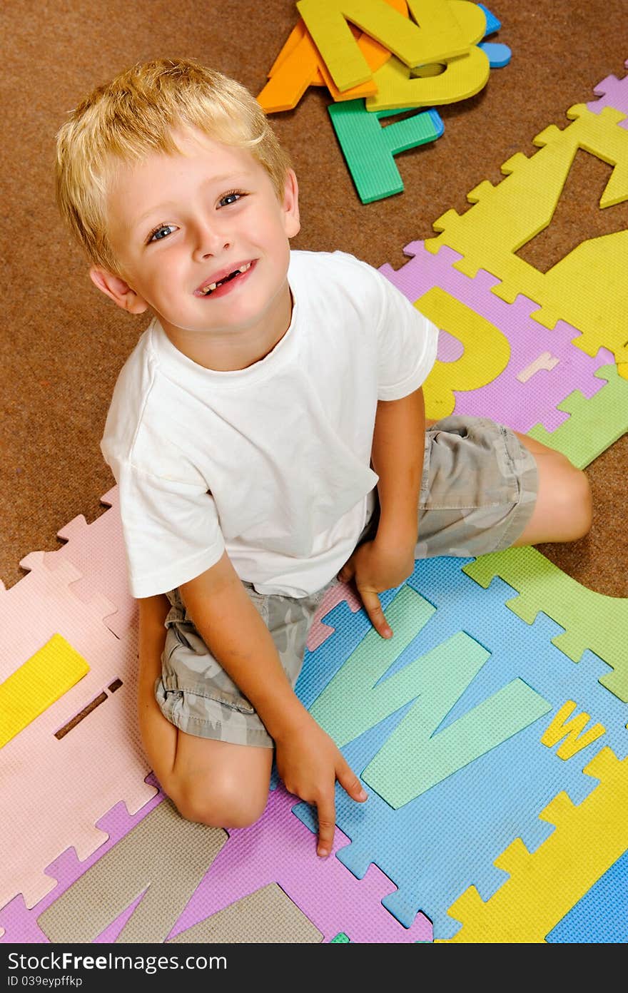 Young blonde boy points to the new letter he has learned from the alphabet. Young blonde boy points to the new letter he has learned from the alphabet.