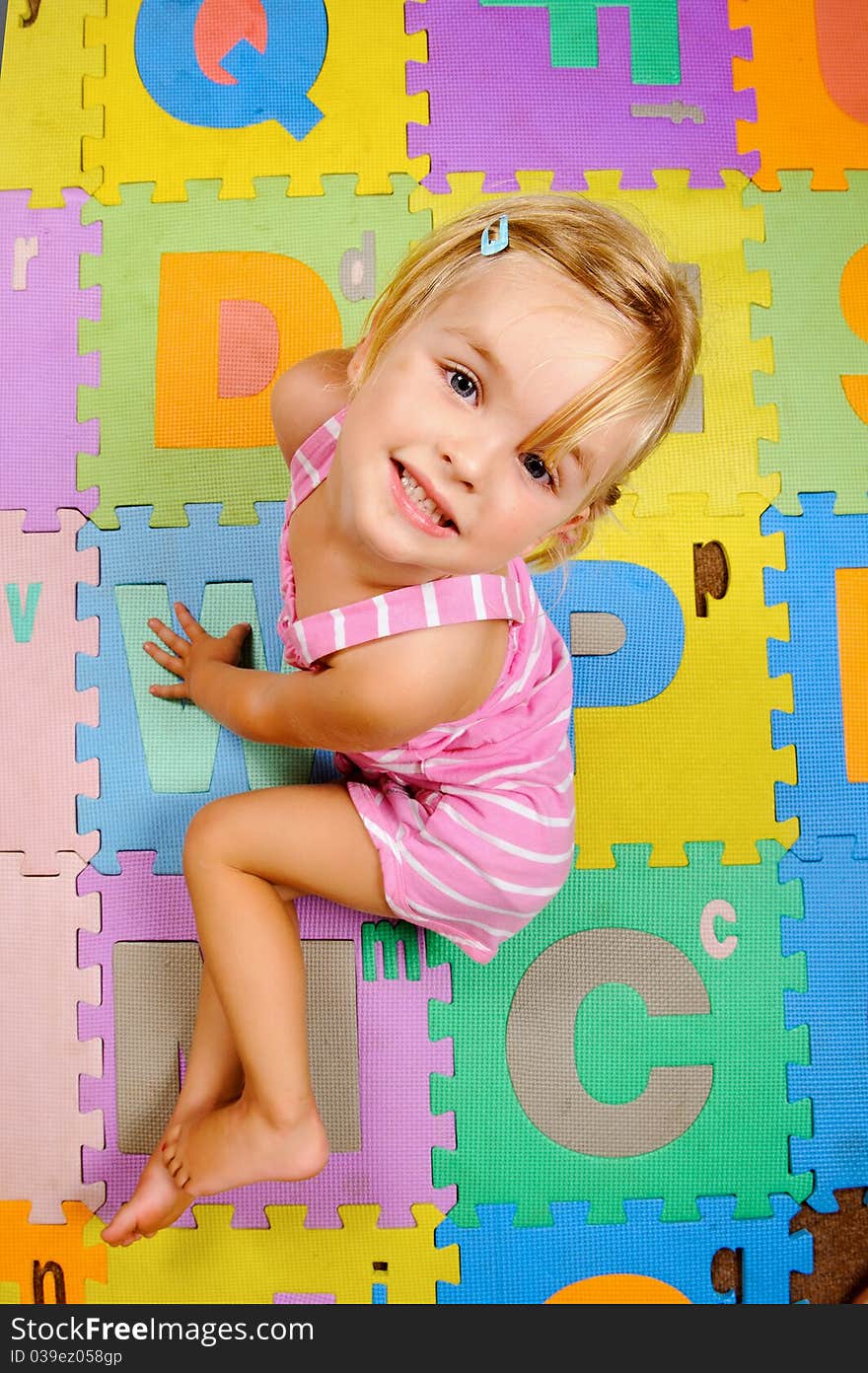 Young blonde girl smiles as she learns the alphabet at playschool. Young blonde girl smiles as she learns the alphabet at playschool