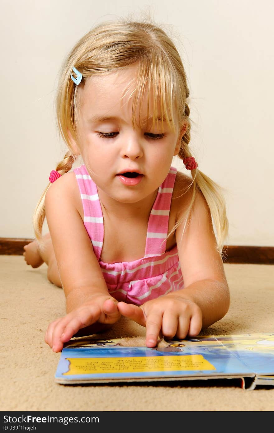 Young adorable blonde girl reads a book on her own. Young adorable blonde girl reads a book on her own