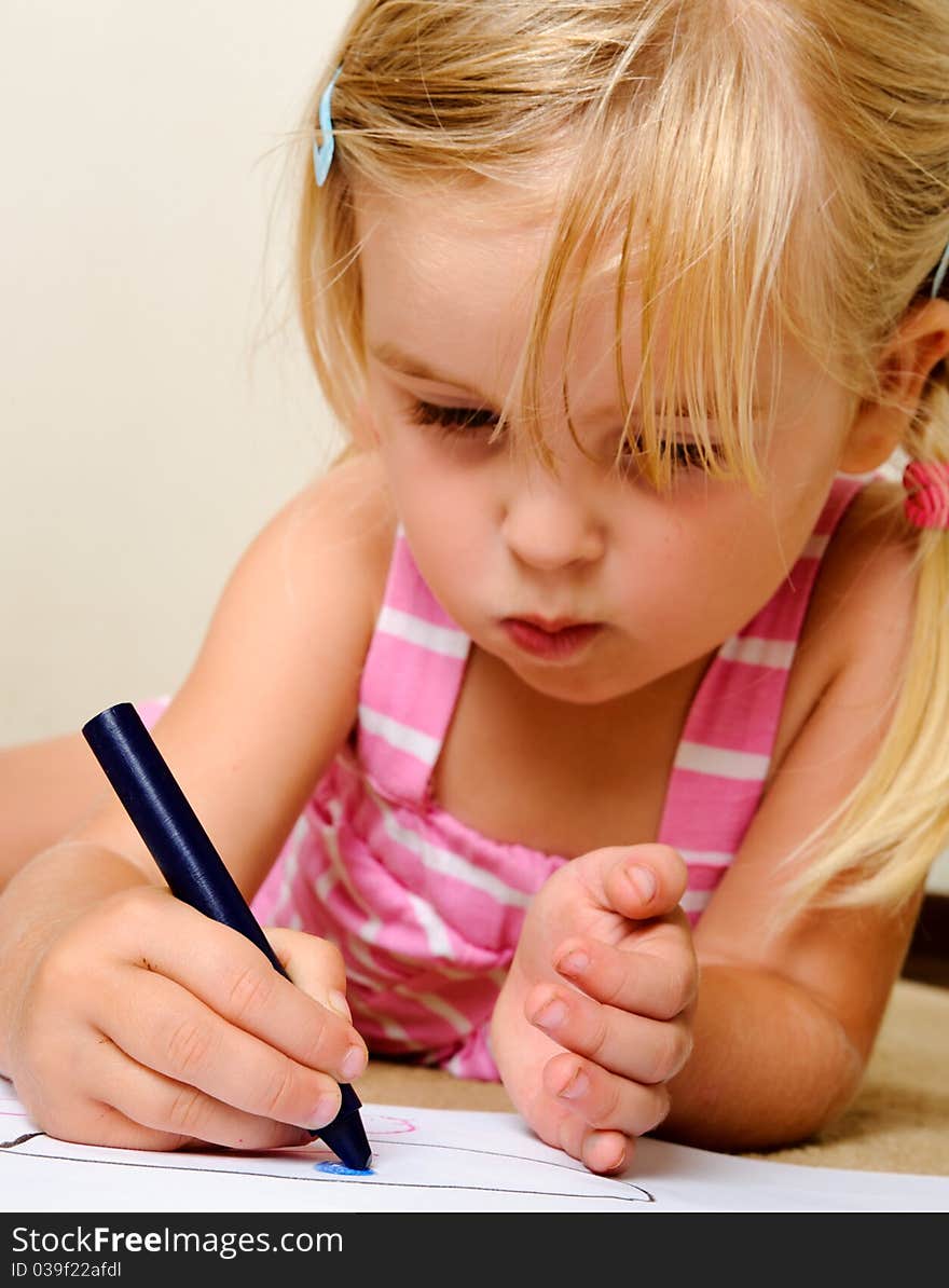 Blonde girl drawing with crayons in school (focus on hand). Blonde girl drawing with crayons in school (focus on hand)