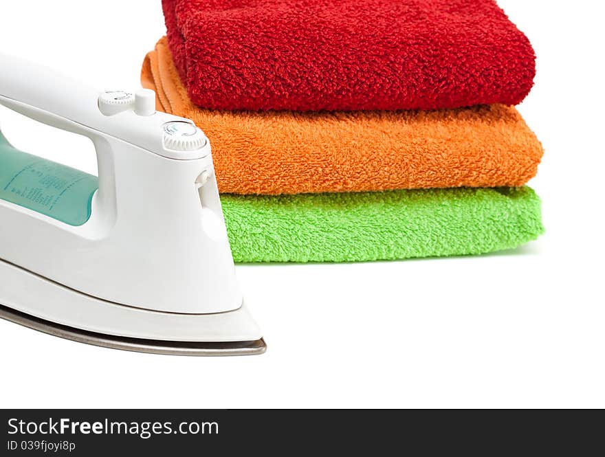 Iron and stacked colorful towels isolated on a white background. Iron and stacked colorful towels isolated on a white background.