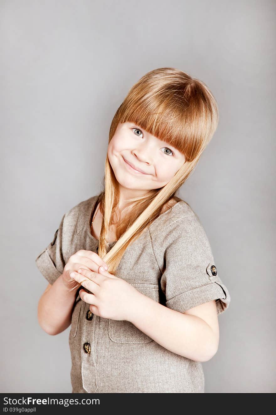 Little girl holding her hair and smiles