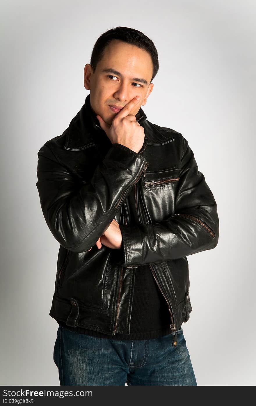 Tough attractive man in thoughtful pose in black leather jacket on white background. Tough attractive man in thoughtful pose in black leather jacket on white background