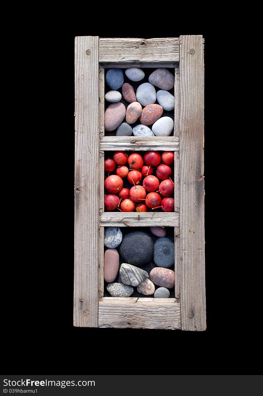 An old window frame with sea stones and little red apples in it. An old window frame with sea stones and little red apples in it.