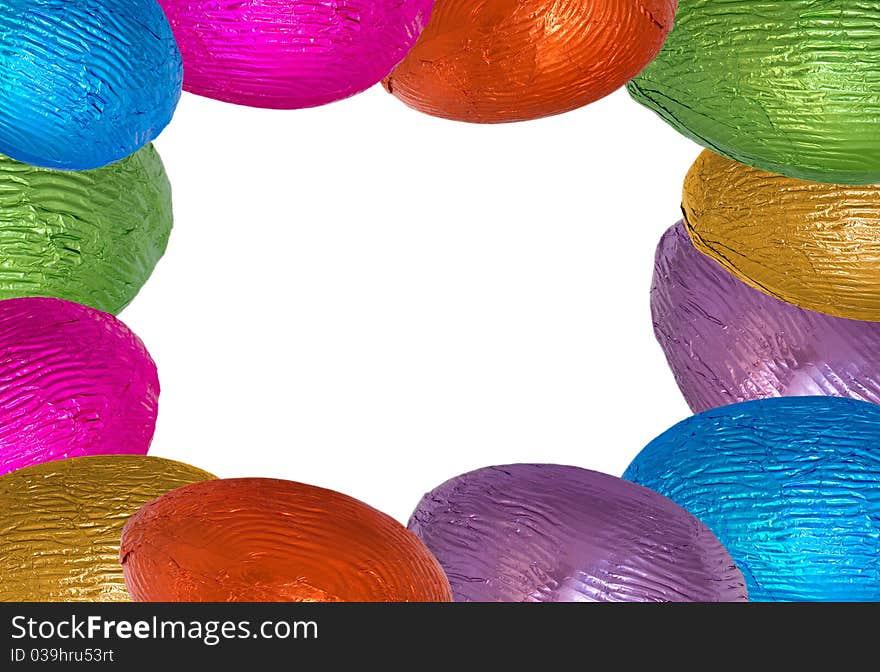 Chocolate easter eggs wrapped in shiny green blue pink gold orange purple foil arranged as border with isolated white in middle. Chocolate easter eggs wrapped in shiny green blue pink gold orange purple foil arranged as border with isolated white in middle