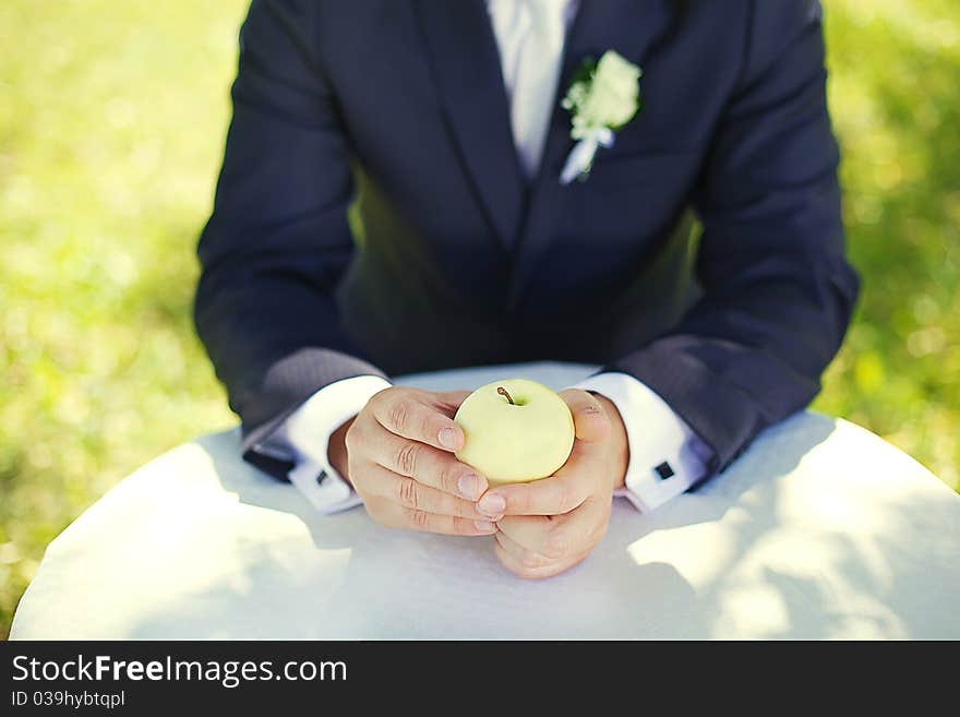 Groom with an apple in the garden