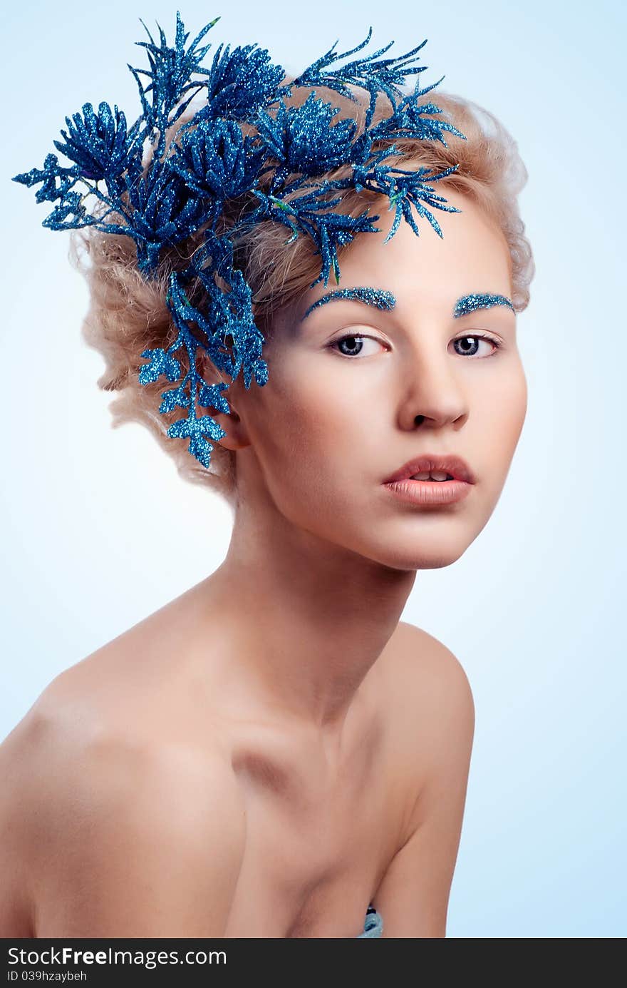 Beautiful winter girl with a blue flower in her hair