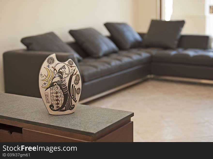 Ornate vase on a sideboard shelf in living with sofa in the background. Ornate vase on a sideboard shelf in living with sofa in the background