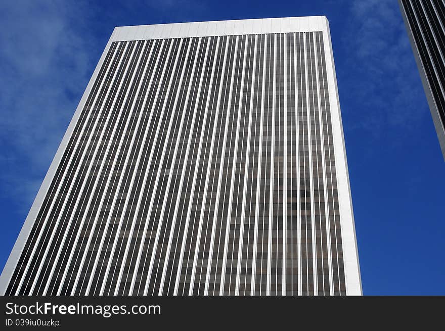 Very tall building looking upward, blue sky with light white clouds, modern architecture. Very tall building looking upward, blue sky with light white clouds, modern architecture