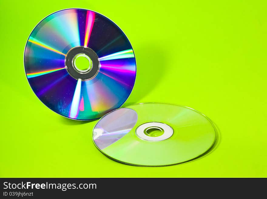 Two CDs and their mirror with green background. Two CDs and their mirror with green background