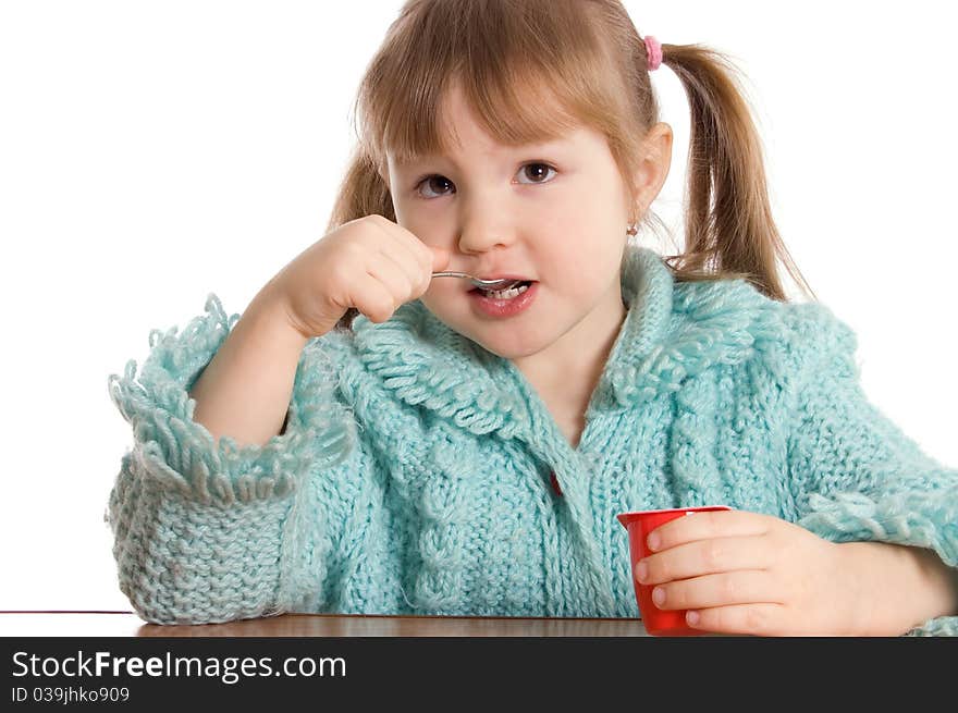 The little girl eats yoghurt on white