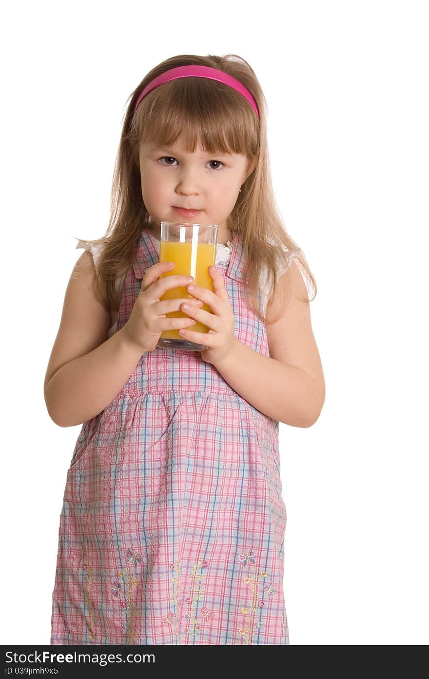 The little girl drinks orange juice on white