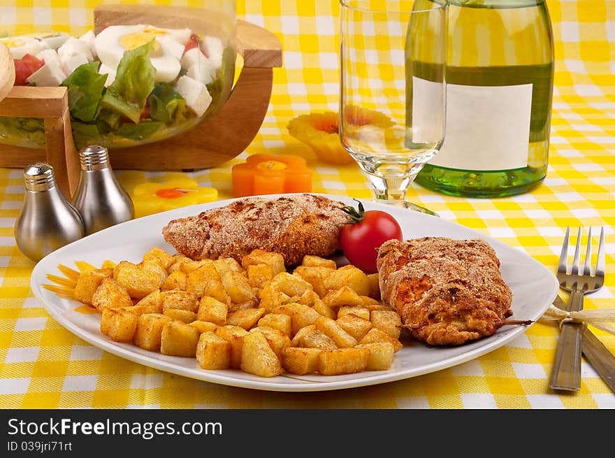 Chicken breast with fried potatoes and salad on a beautiful spring looking table setting