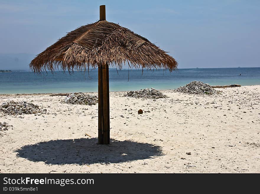 Palm umbrella on the white sand beach